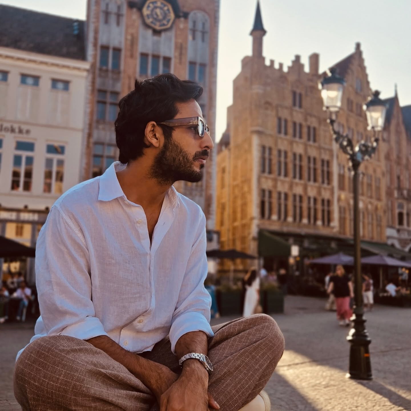 Hamza Chishti seated in a European town square at golden hour